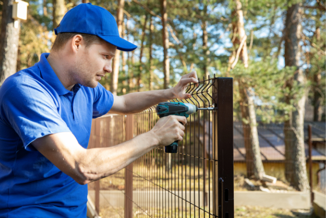 Fence Installation by a worker with a poweer tool